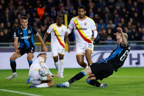 Joaquin Seys slides to shoot and score for Brugge as Lens players close in