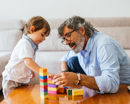 child and grandfather playing with colourful building blocks