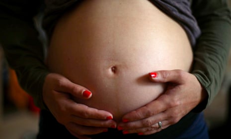 A close up image of a pregnant woman holding her stomach