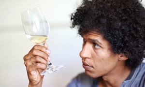 Man holding a glass of white wine looking at the quality of the wine in the glass