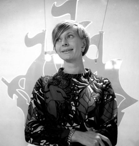 Black and white photo of a young Biddy Baxter in 1968, with a faded Blue Peter ship logo in the background