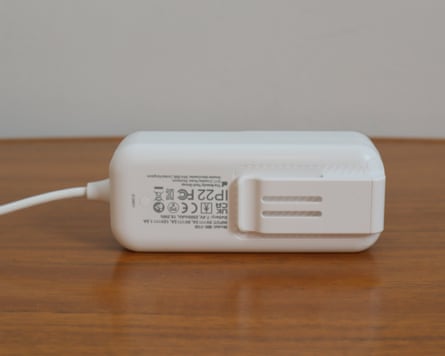 A white CurrentBody Series 3 power bank with charging cable sits on a wooden table