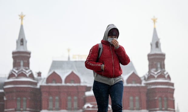 A woman walks along a street in central Moscow, Russia in January. She wears a red coat.