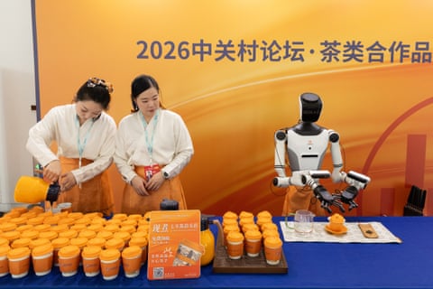 Workers and a robot prepare tea beside each other at a booth at the 2026 Zhongguancun Forum earlier this year. China’s rollout of AI has sparked concerns about the future of the jobs market.