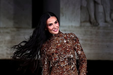 Demi Moore wearing a glittery, metallic-patterned dress and swinging her long black hair