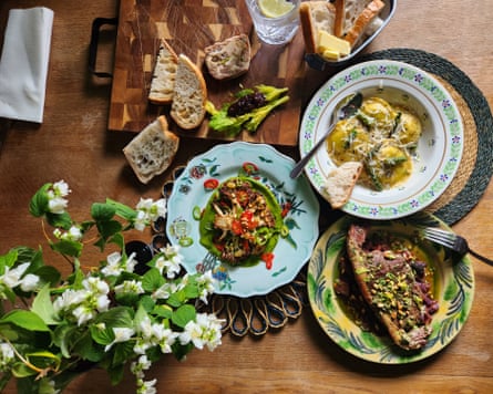 Food presented on pretty plates, with a bread board in the background and flowers on the table.