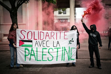A demonstrator holds up flares as two other hold a banner reading in French "Solidarity with Palestine" during a pro-Palestinian demonstration in the courtyard of Sciences Po building in Lyon, on Tuesday.