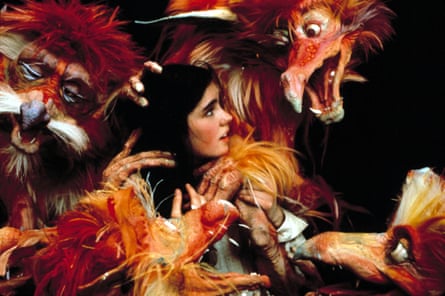 A dark haired girl surrounded by orange, furry puppets.