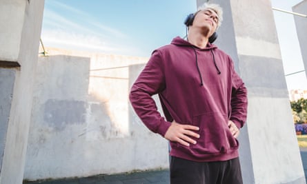 A runner wearing headphones warms up by doing neck stretches.