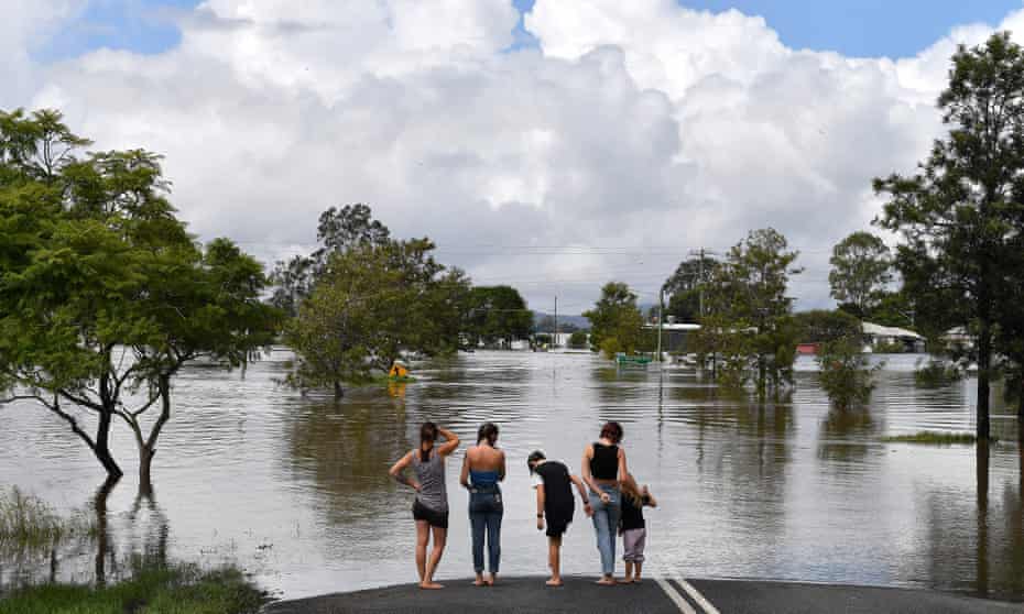A family looks out over a flooded street in Lawrence, northern NSW