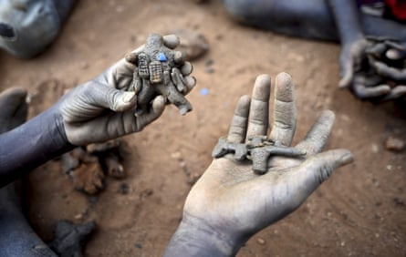 A child’s hands hold a small clay figure of a fighter and a small clay machine gun