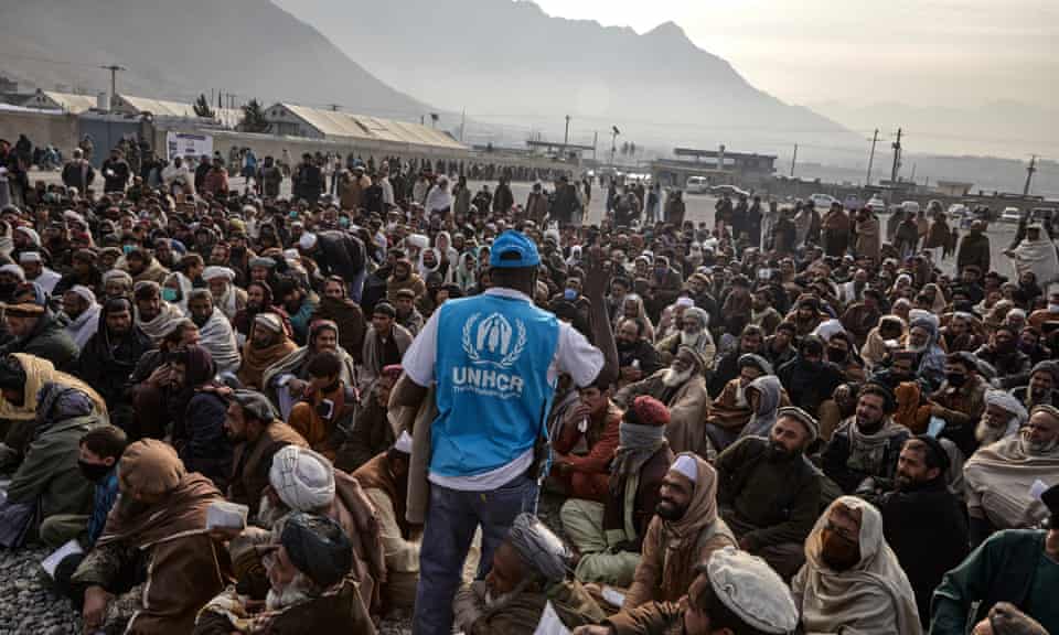 A UNHCR staff member assists displaced families waiting to receive winter cash assistance in Kabul.