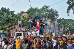 A crowd surround a large idol of the goddess Kali