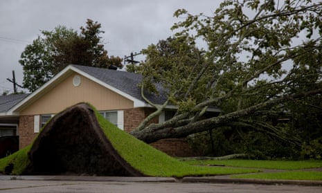 An uprooted tree lays on a house as Hurricane Ida hits Morgan City, Louisiana.