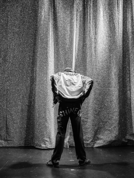 Danny Sloggett on stage in front of a curtain with his back to the audience