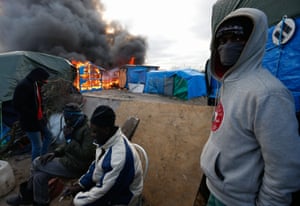 Refugees in front of a burning shelter.