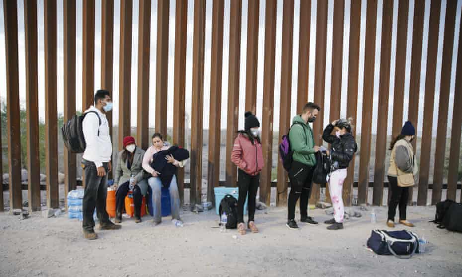 Asylum seekers from India, Cuba and Colombia wait next to the USA border wall with Mexico, while being processed by USA border patrol in Yuma, Arizona, on 22 February 2022.