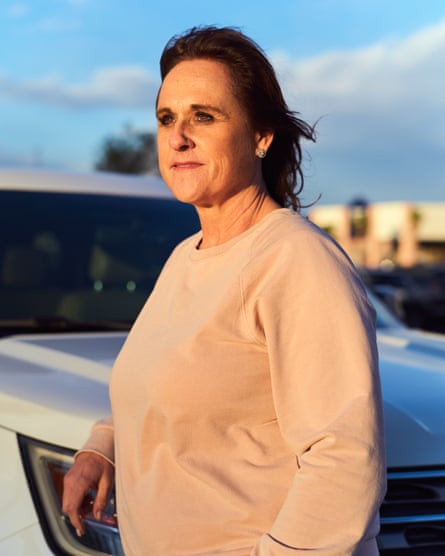 Woman in pale pink sweater standing by car