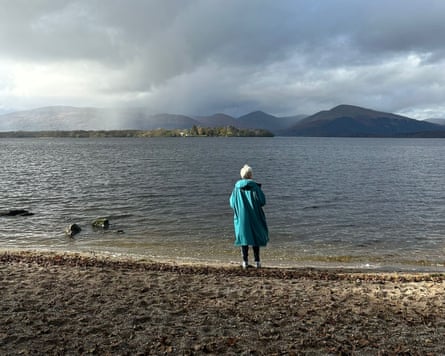 Woman with grey hair gazing across a loch in Scotland in rainy weather
