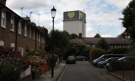 Grenfell Tower in its white shrouding with the green heart logo at the top, seen from a neighbouring street