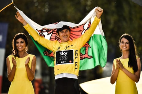 Geraint Thomas holds the Welsh flag as he celebrates on the podium.