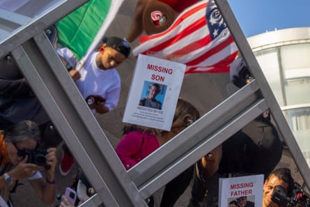Marchers stop to look at flyers with photos of people who have been arrested by Ice.
