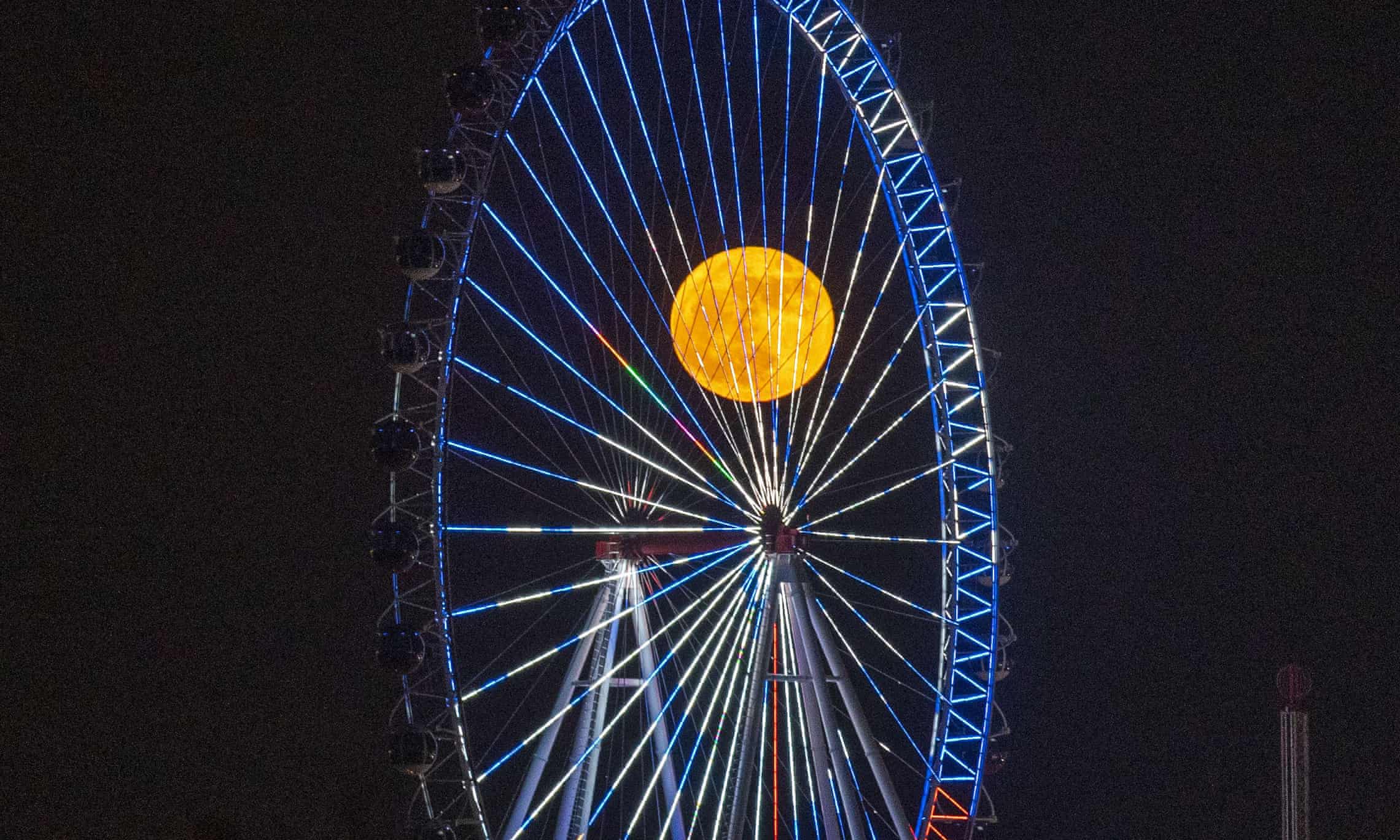 Antalya, Turkey. The moon, large and yellow, is seen through the struts of a Big Wheel
