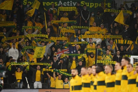 Феновете държат шалове над главите си, докато soccerros, на преден план, вдигат ръце по време на националния химн