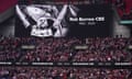 Fans in a stadium stand beneath a screen showing a picture of Rob Burrow and the words: 'Rob Burrow CBE, 1982-2004'