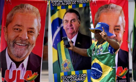 A demonstrator dressed in the colours of the Brazilian flag performs in front of a street vendor's towels for sale featuring the images of Luiz Inácio Lula da Silva and Jair Bolsonaro in Brasilia. Photograph: Eraldo Peres/AP