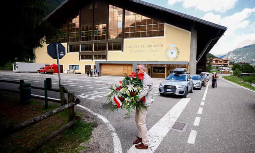 Um homem carrega flores em Canazei.