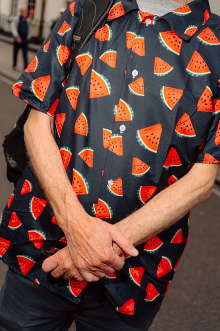 A man wearing a black t-shirt scattered with watermelons