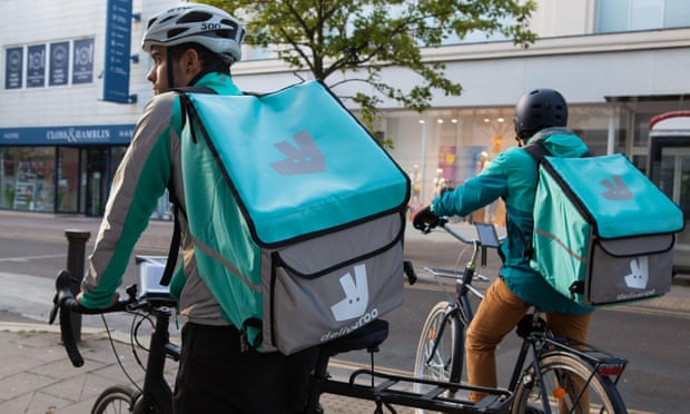 Two Deliveroo cycle couriers riding past with their big turquoise delivery rucksacks