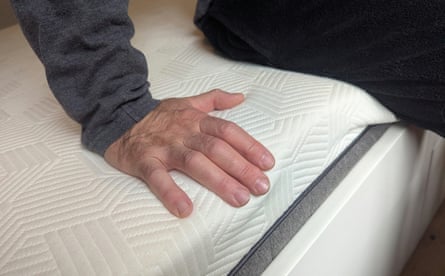 A man sits on the edge of a Panda Hybrid Bamboo Mattress