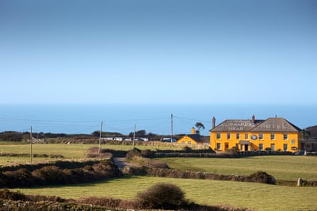 A large bright yellow pub with the sea in the background