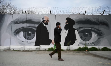 A man walks past a mural of the US special representative Zalmay Khalilzad, left, and the Taliban co-founder Mullah Abdul Ghani Baradar in Kabul