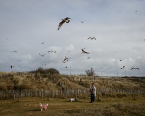 A woman walks her dogs near the coast at Ouistreham.