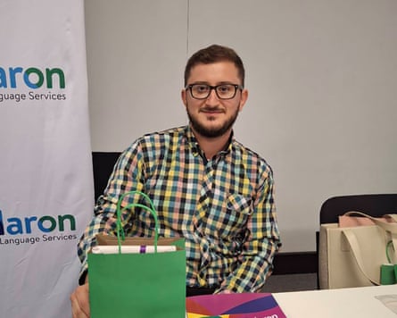 Daniel Martin sits at a table, smiling, with a green gift bag beside him