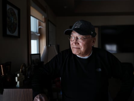 Solomon Atlookan looks out the window of his office. He wears a baseball cap and black jumper.