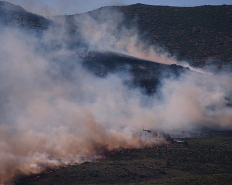 A firefighting helicopter drops water on the flames as a wildfire advances near Burgohondo, Ávila province, Spain.