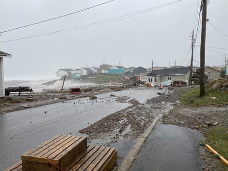 A wooden house by the sea pushed into the middle of a road by a storm