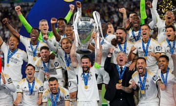 Nacho Fernández of Real Madrid lifts the Champions League Trophy alongside his teammates and the manager Carlo Ancelotti.