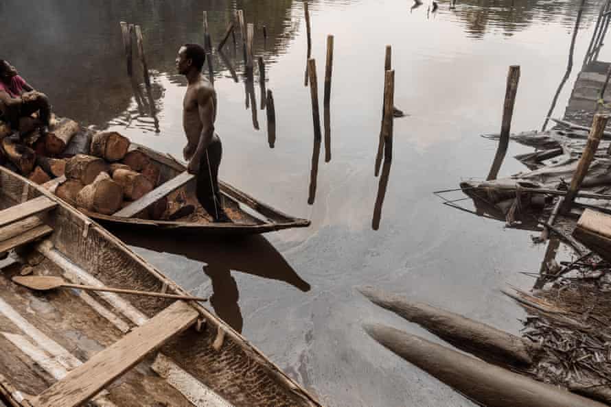 A man and woman in a canoe floating on an oily river in Bayelsa, Nigeria, 8 June 2018