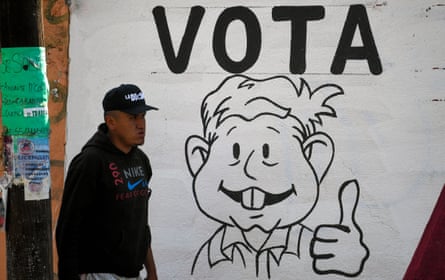 A man in Chimalhuacán walks past a wall with a graffiti promoting the vote.