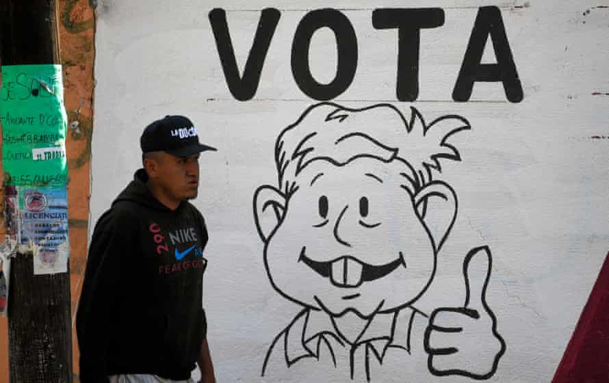 Una persona en Simalhuan cruza una pared con grafitis que promueven el voto.