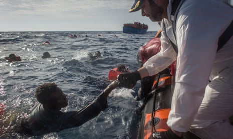 Crew members from the Moas Phoenix vessel help survivors into a rescue boat