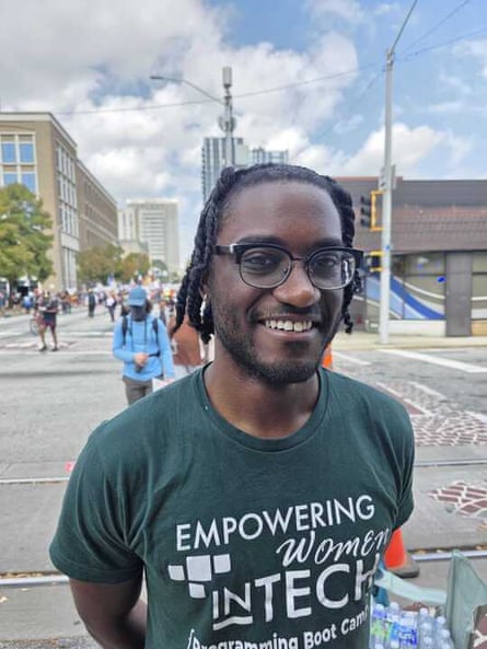 man smiles outside at protest with a shirt saying ‘empower women in tech’
