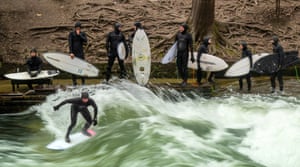 Surfers stand in icy temperatures with their boards at the Eisbach iwave n the heart of the Bavarian capital of Munich.