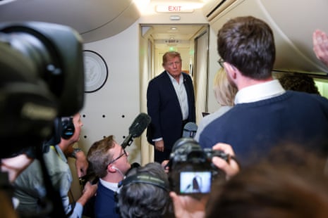 Donald Trump stands in a corridor aboard Air Force One as he looks at a group of reporters