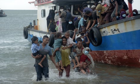 Locals rescue Rohingya refugees from a ship on Lancok beach, Indonesia